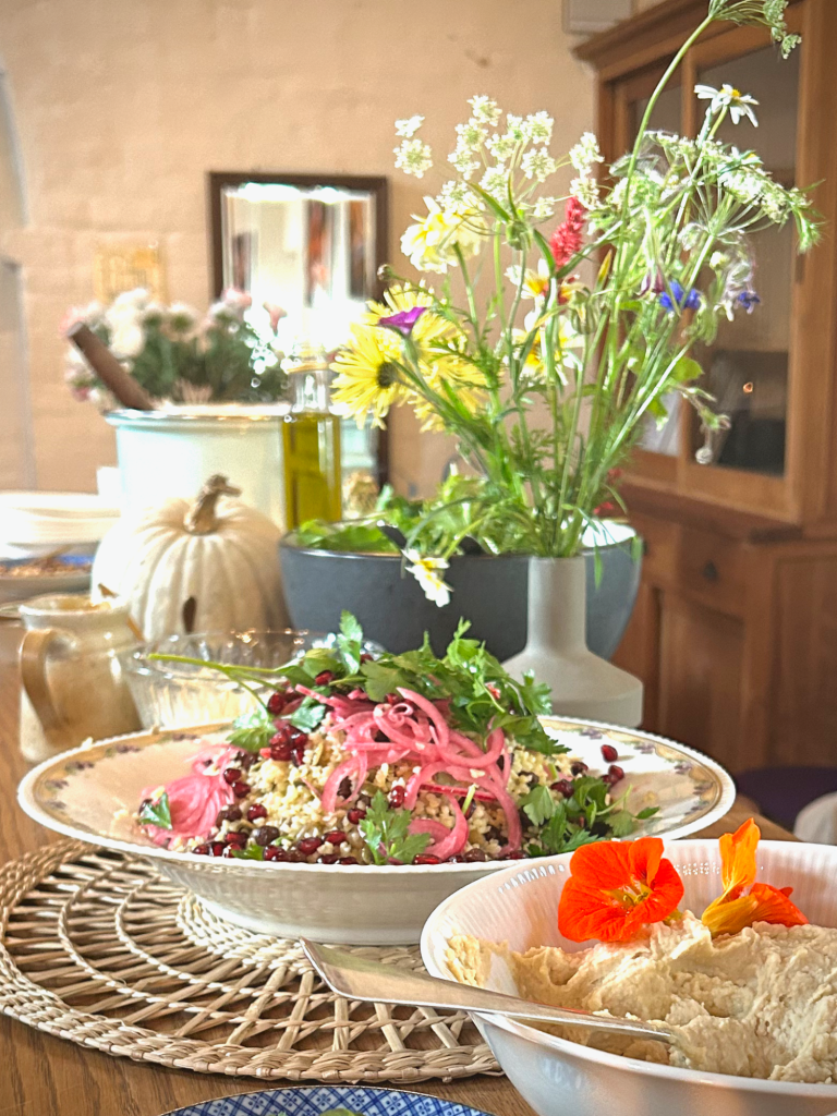 Een kleurrijke salade met groente, geserveerd op een houten tafel met bloemen op de achtergrond.